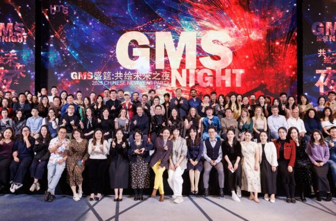 Large group of tms employees posing for a photo on a stage