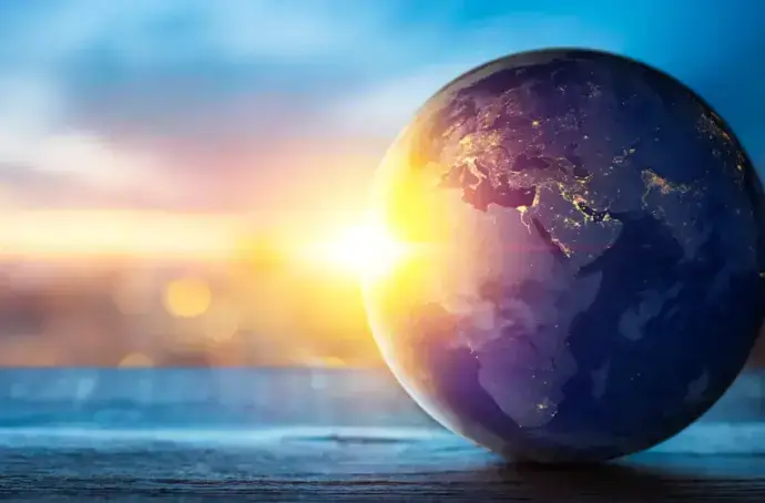 Globe terrestre sur une surface en bois avec un coucher de soleil en arrière-plan