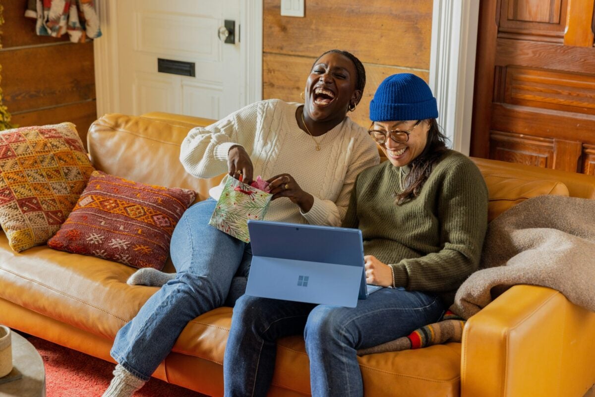 two people sitting on a couch with laptop