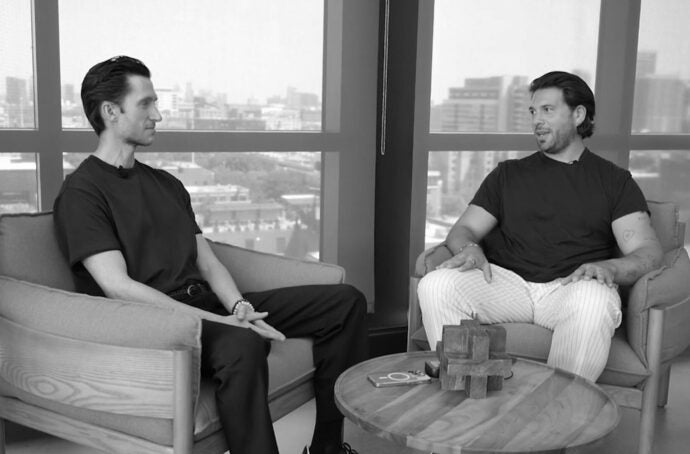 Two men having a conversation sitting down with the city in the background