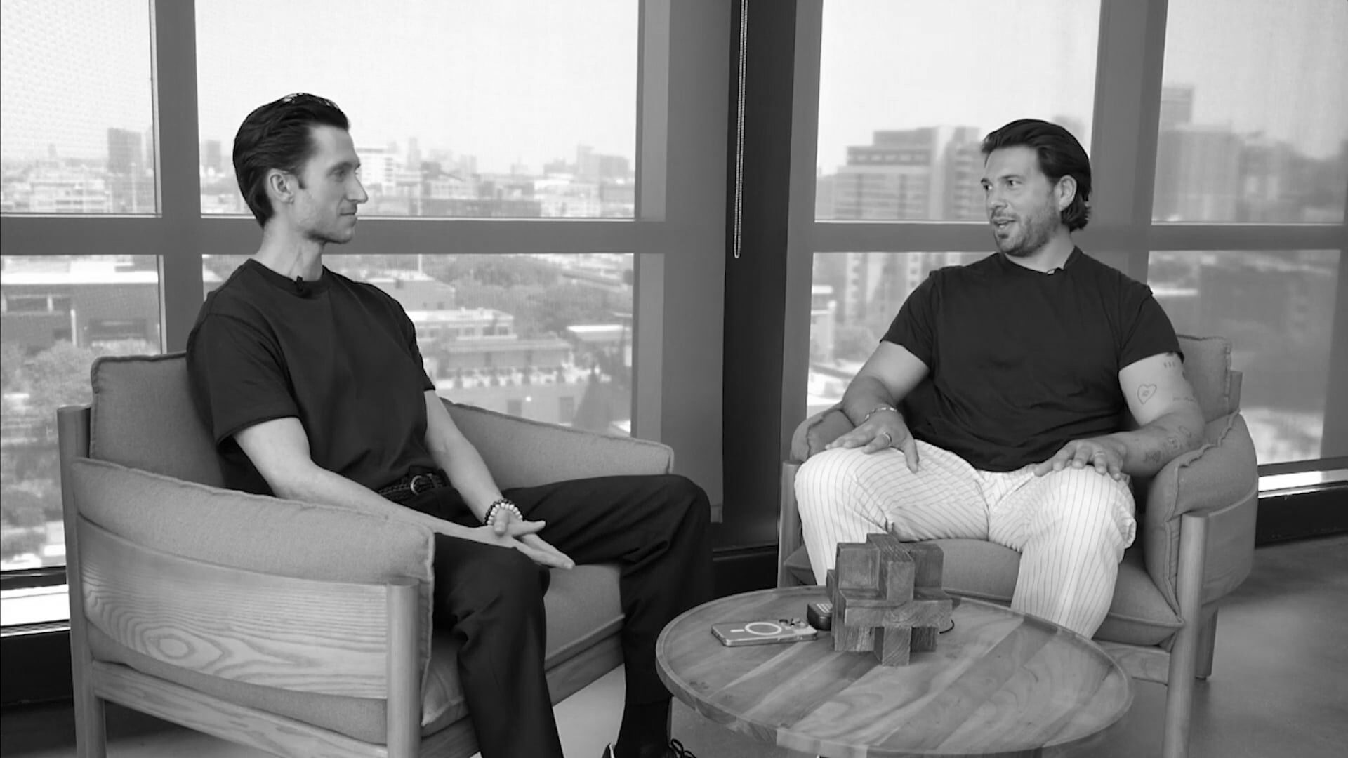 Two men having a conversation sitting down with the city in the background