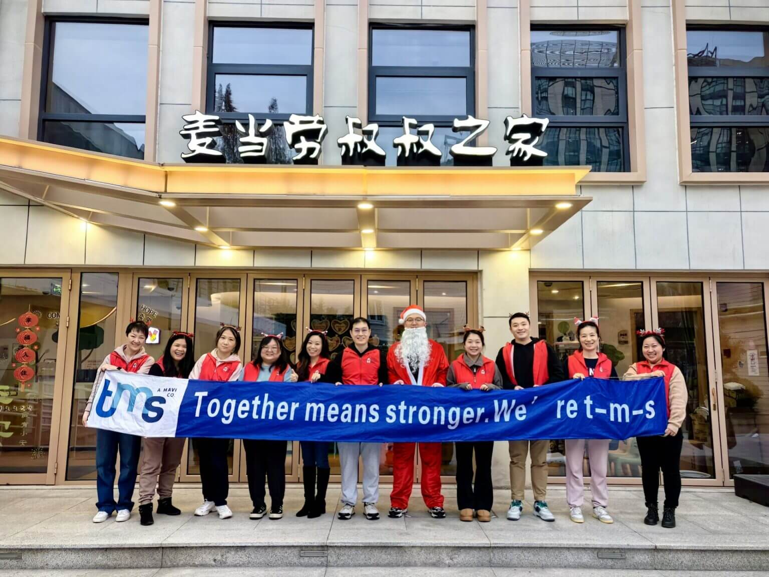 employés de tms tenant une bannière sur laquelle il est écrit « together means stronger » (ensemble, nous sommes plus forts)