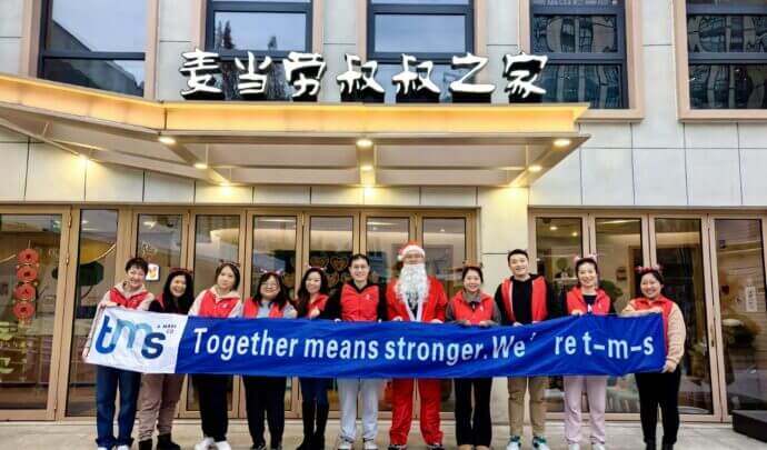 tms employees holding up a "together means stronger" banner
