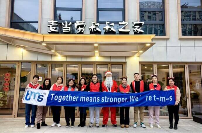 employés de tms tenant une bannière sur laquelle il est écrit « together means stronger » (ensemble, nous sommes plus forts)